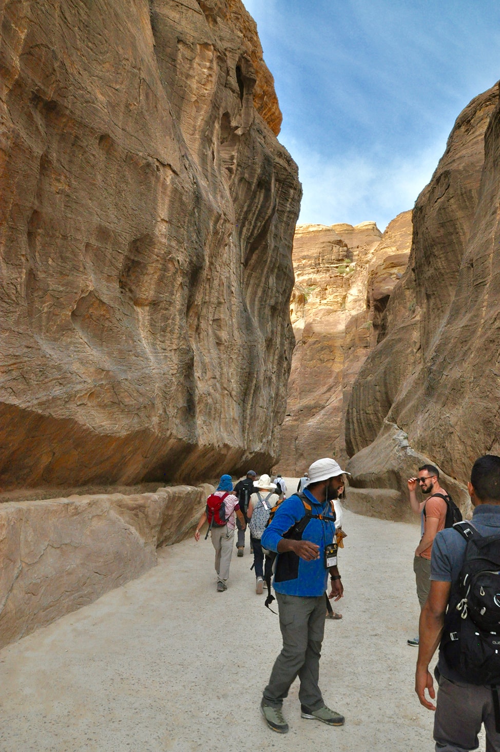 High rock formations frame the picture as I approach Petra's Treasury building with my tour group in Jordan