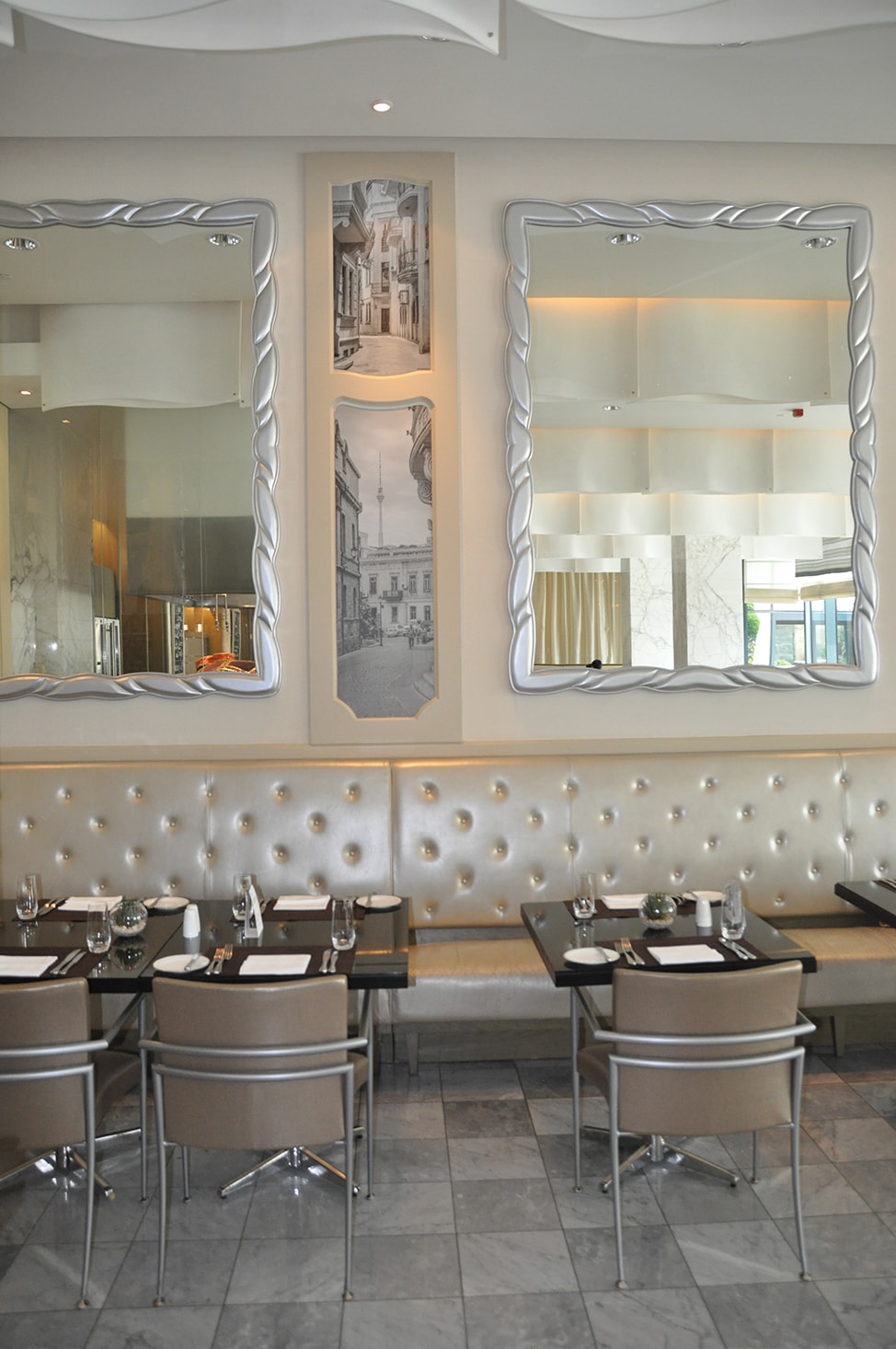 Large silver framed mirrors line the walls above a banquet sitting area at Le Bistro