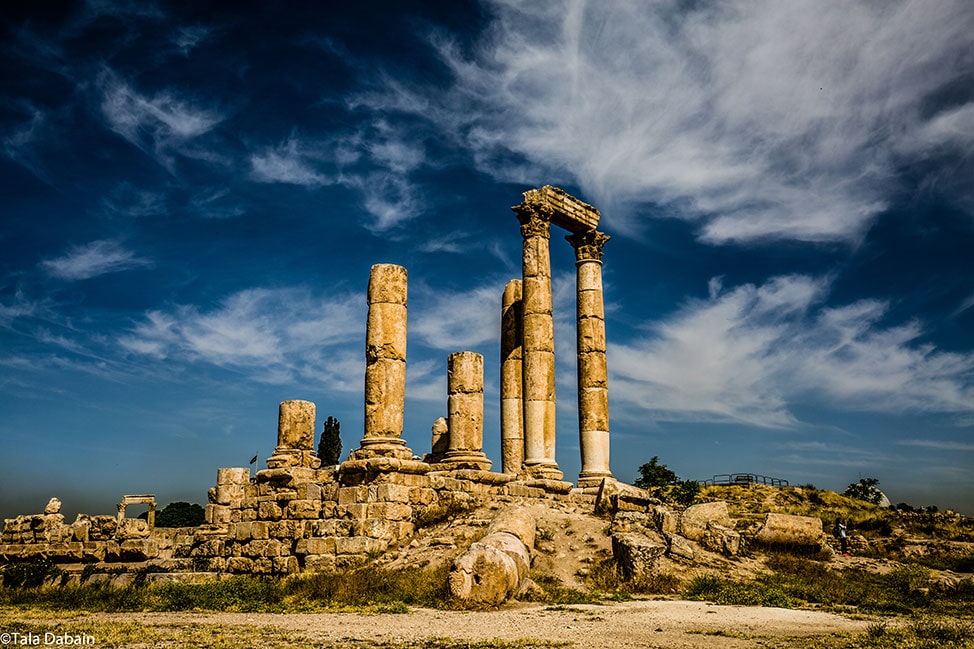 Tall pilars against a bright blue sky mark the historic Citidel site in the city of Amman, Jordan.